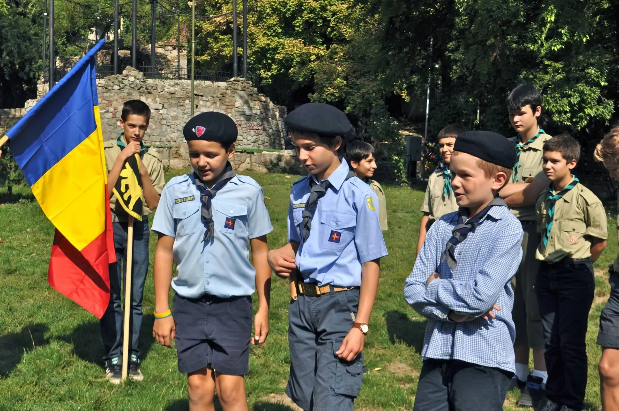 Lupișori în uniformă albastră lângă drapelul României.